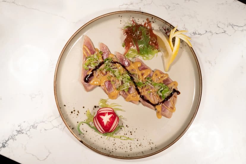 Hamachi carpaccio on a round plate over marble