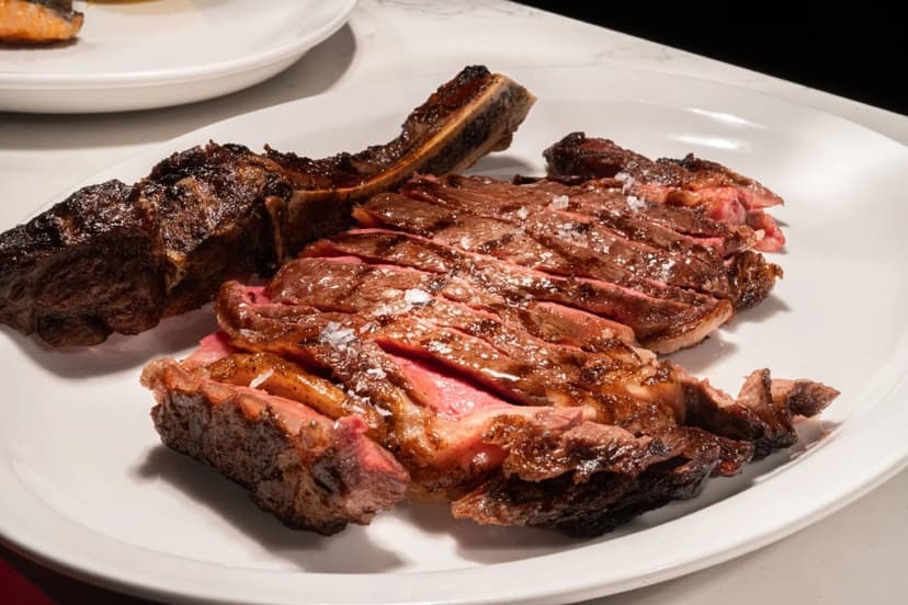 A sliced bone-in ribeye steak, seared dark and finished with flaked sea salt